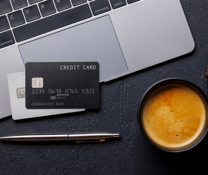 Business credit cards stacked on a laptop next to a cup of coffee representing business credit card stacking strategy